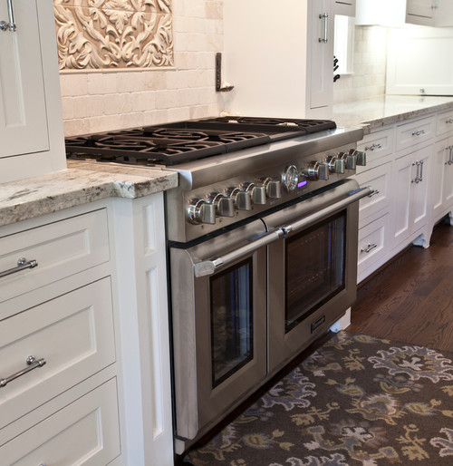 River White Countertop with Custom Made White Cabinets,Tumbled Travertine Subway Backsplash , Travertine Inlayed Carved Tiles and Red Oak Flooring